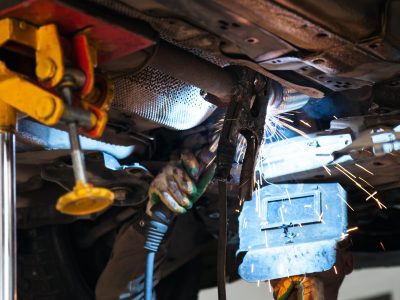 welder welds silencer on exhaust pipe